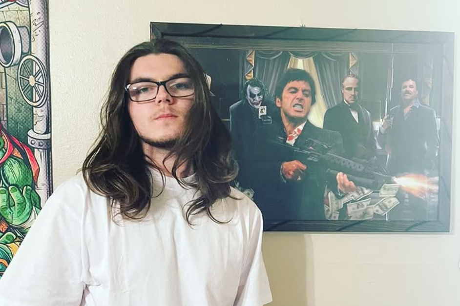 Baby Gos standing in front of a frame with a mob gangster shooting a machine gun.