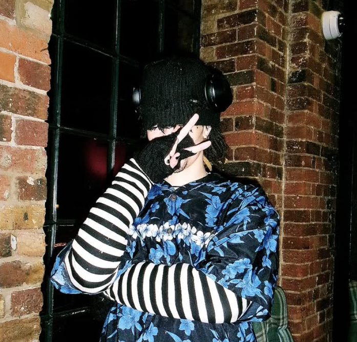 10r holding the peace sign in front of a window