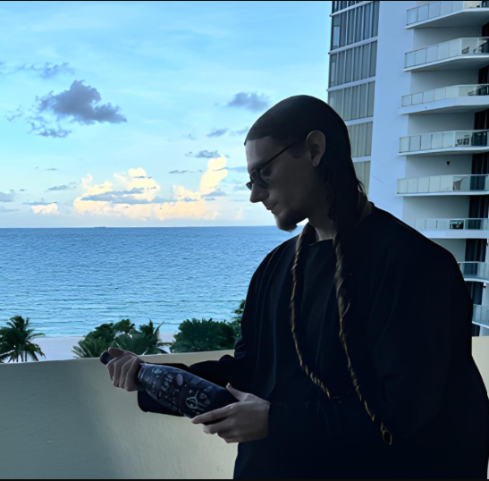 Vicious Teknique holding an expensive bottle of alcohol in front of the Miami sunset.